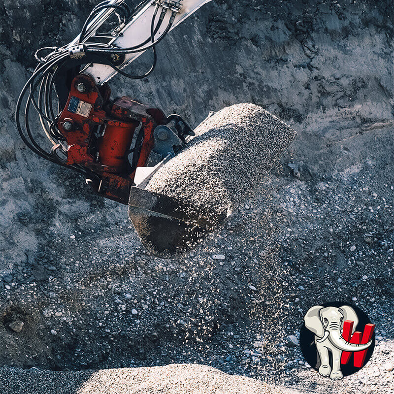 Baggerschaufel lädt Kies auf.